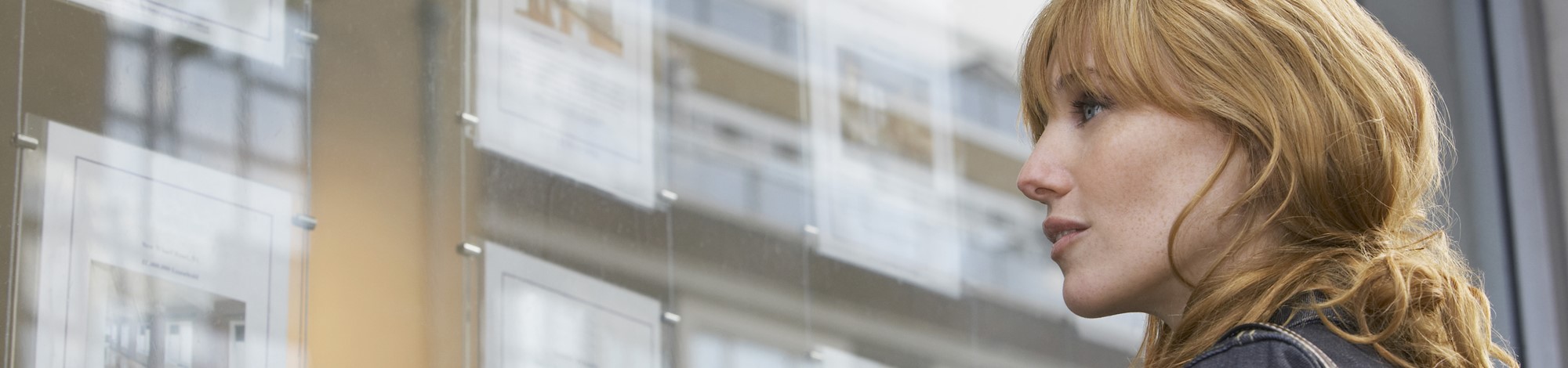 Girl looking for a place to rent in letting agent window