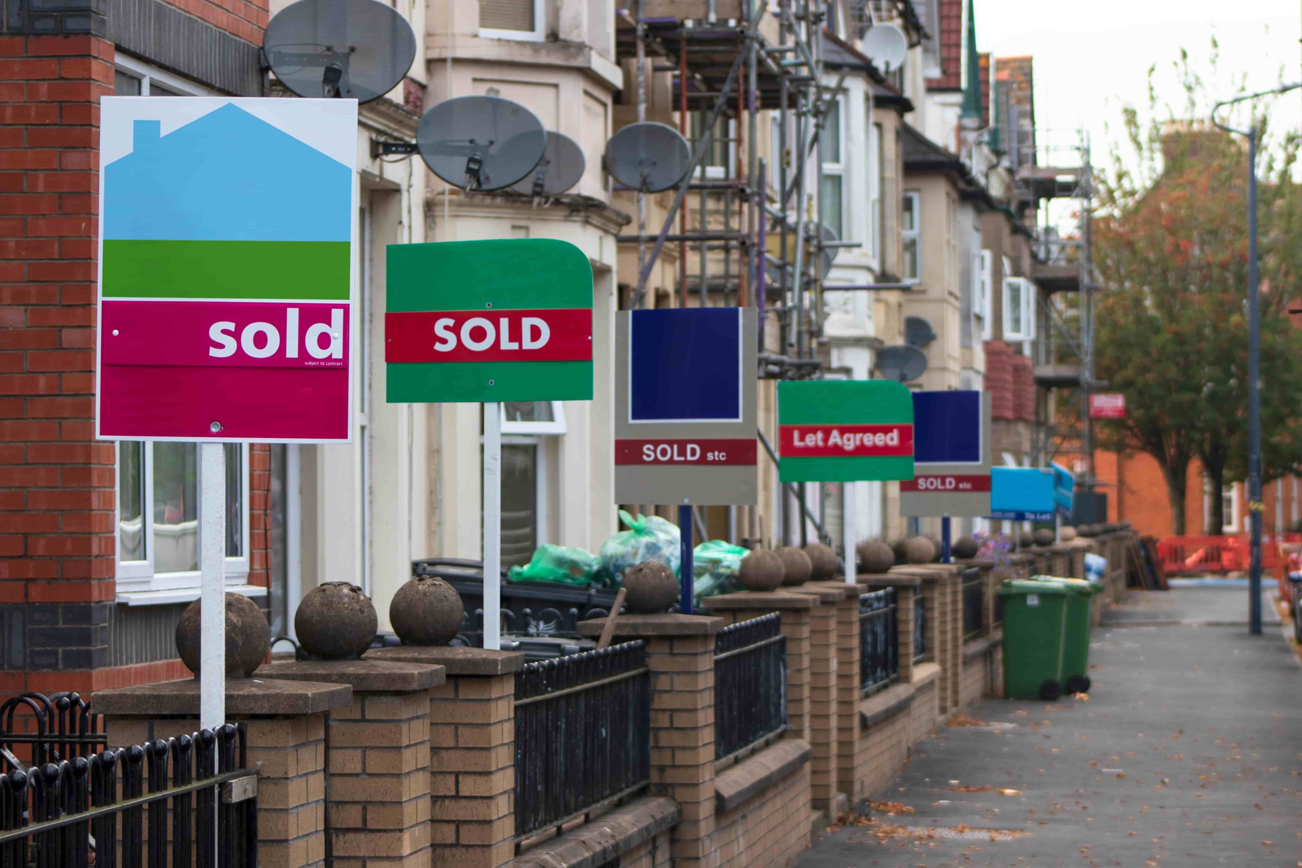 estate agent for sale signs down a uk residential street