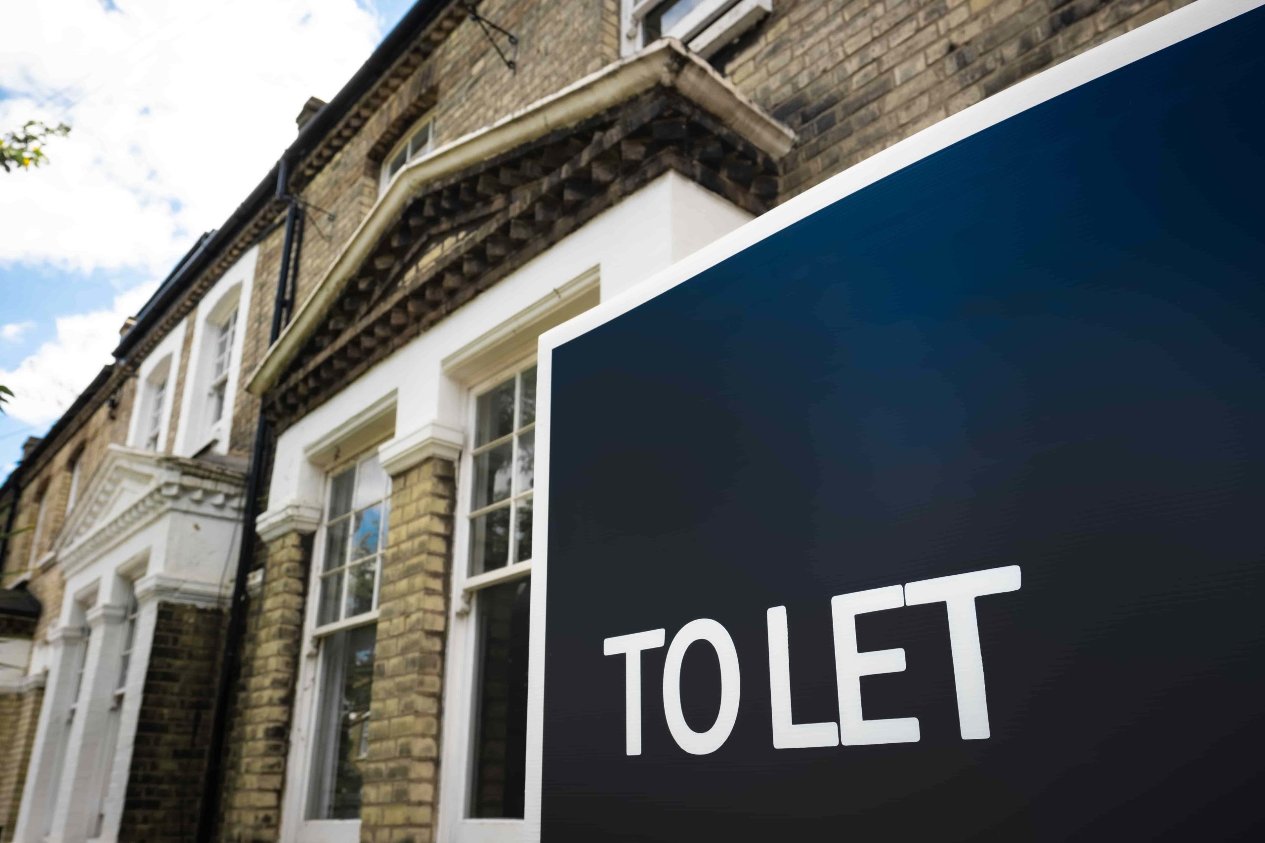 Estate agency 'To Let' sign board on street of British houses