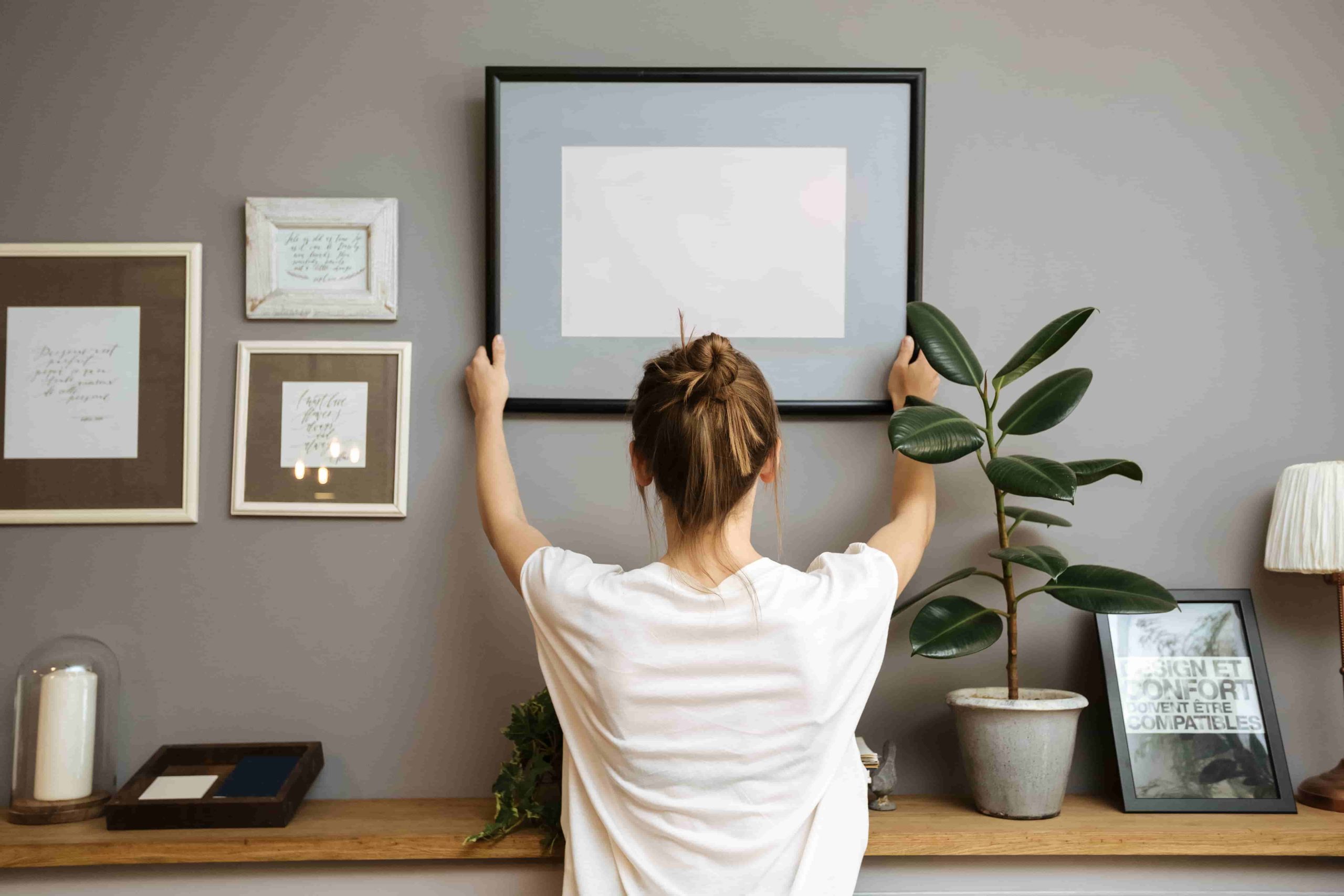 Woman hanging a framed picture