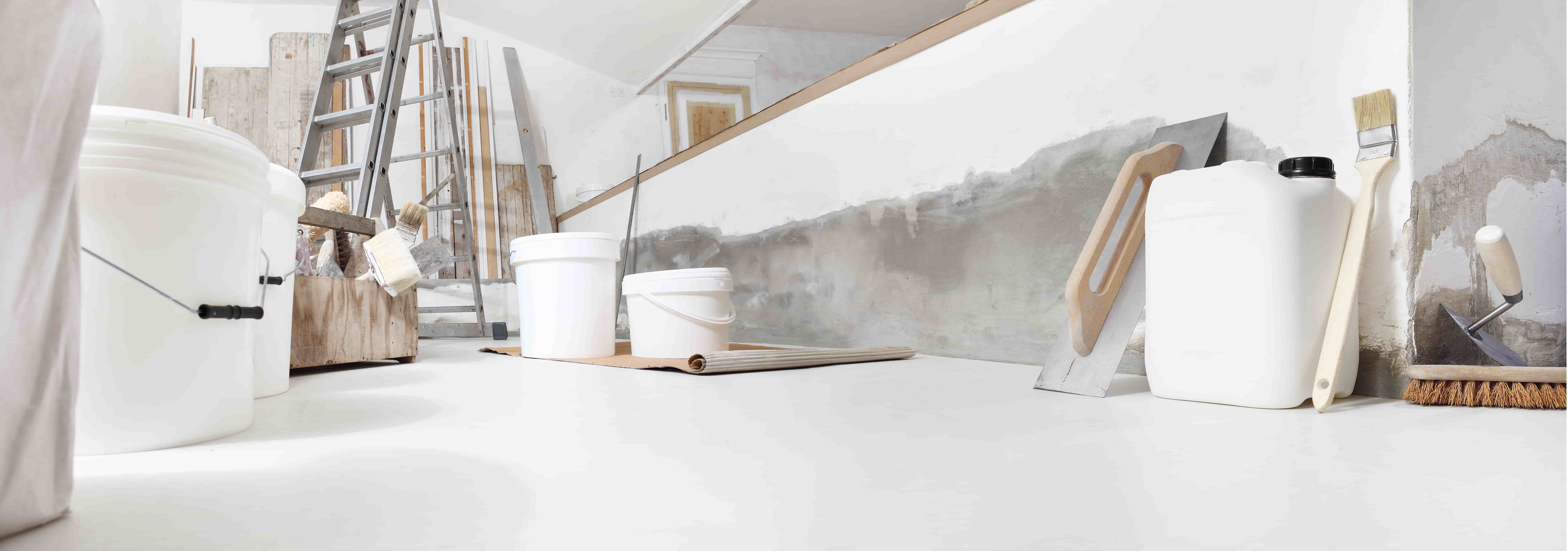 Low angle of indoor shot of construction or building site of home renovation with tools on white floor with paint buckets