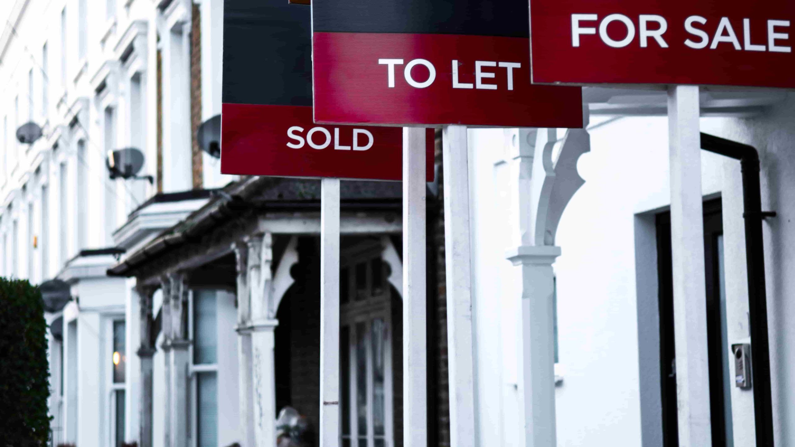 Estate agent 'for sale', 'to let' and 'sold' signage boards of street of terraced houses