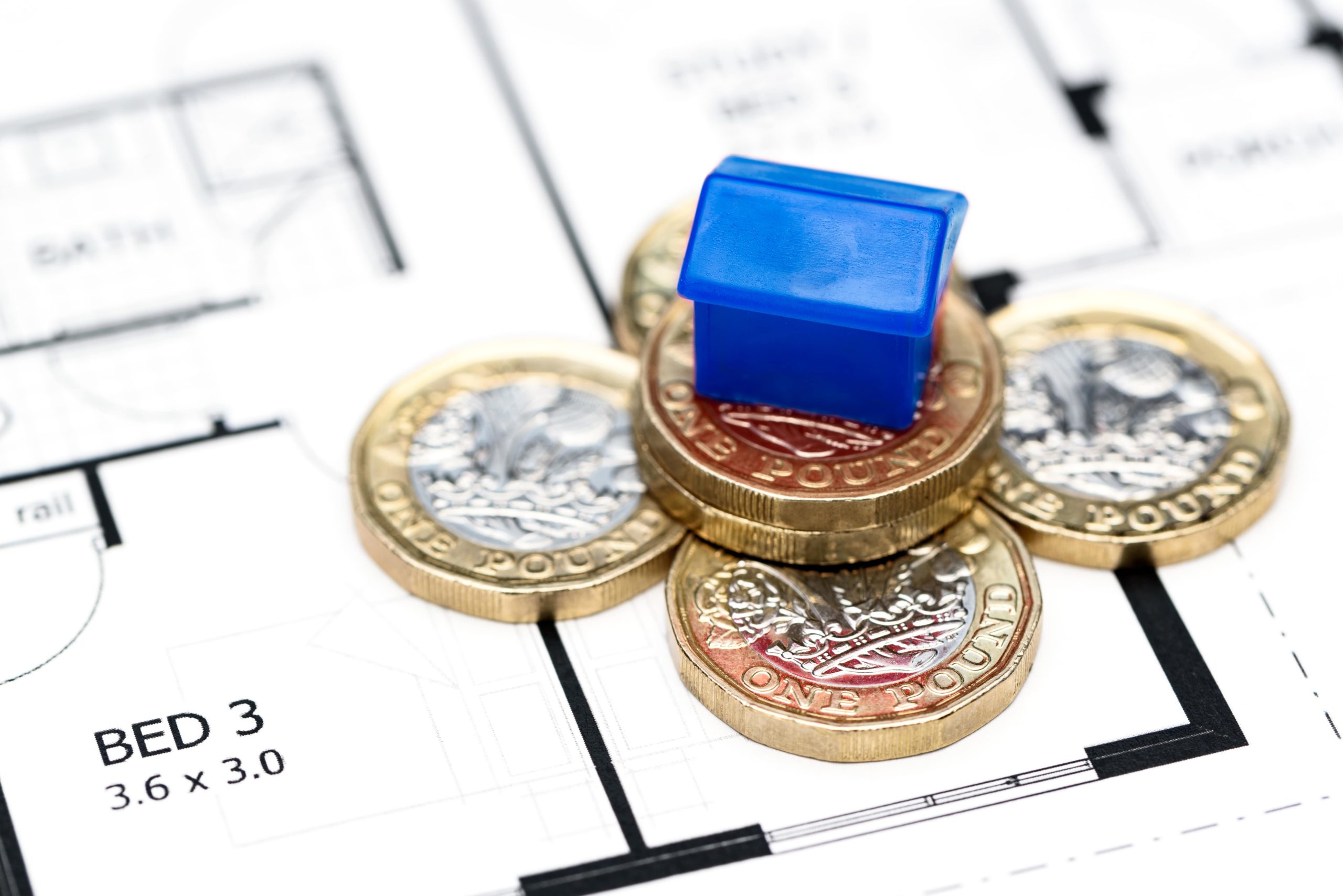 small blue house on stack of pounf coins - buying a house with cash