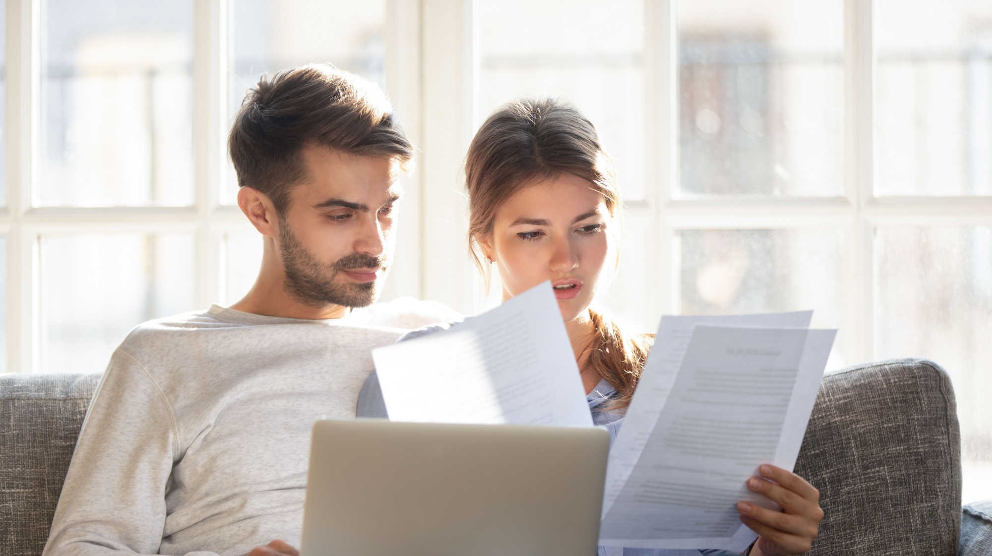 couple-sitting-on-couch-going-through-bank-statements-for-mortgage-2