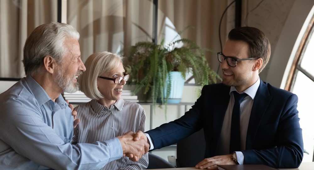 happy-elderly-married-couple-shaking-hands-discussing-the-searches-when-buying-a-house-with-estate-agent-3